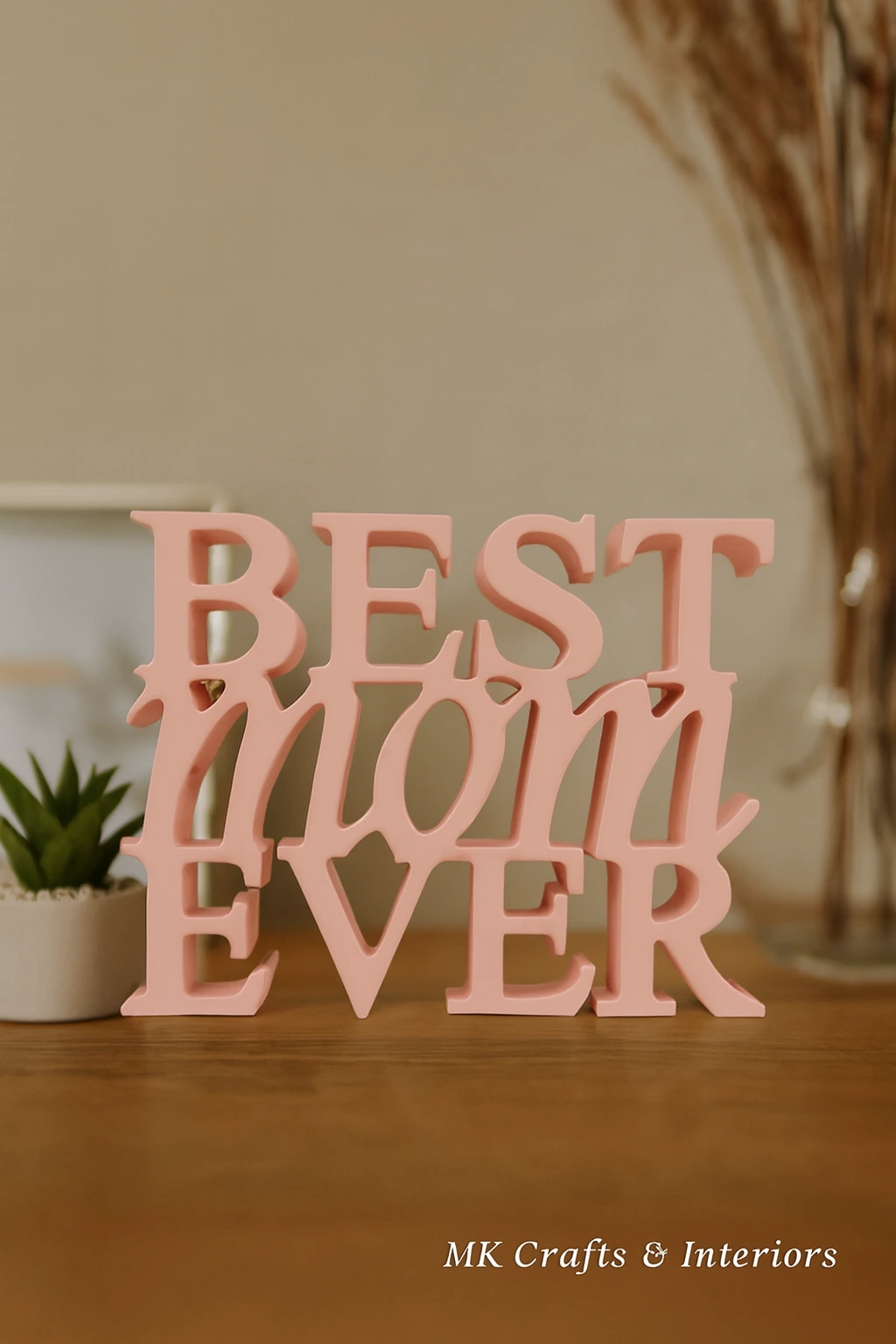 Light pink wooden “Best Mom Ever” decorative showpiece by MK Crafts displayed on a table with plant décor – handcrafted mother gift item.