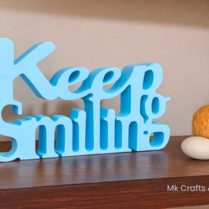 Light blue “Keep Smiling” wooden decorative showpiece by MK Crafts & Interiors in Hyderabad placed on shelf – motivational home décor gift.