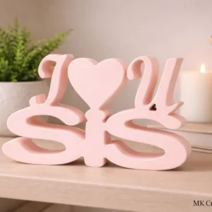 I Love You Sis light pink wooden decorative tabletop with heart detail by MK Crafts & Interiors Hyderabad displayed on a wooden shelf.